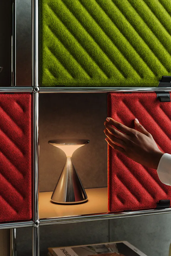 USM Haller Regal bestückt mit USM Haller Soft Panels. Eine Hand berührt ein Soft Panel, um es zu verschieben.